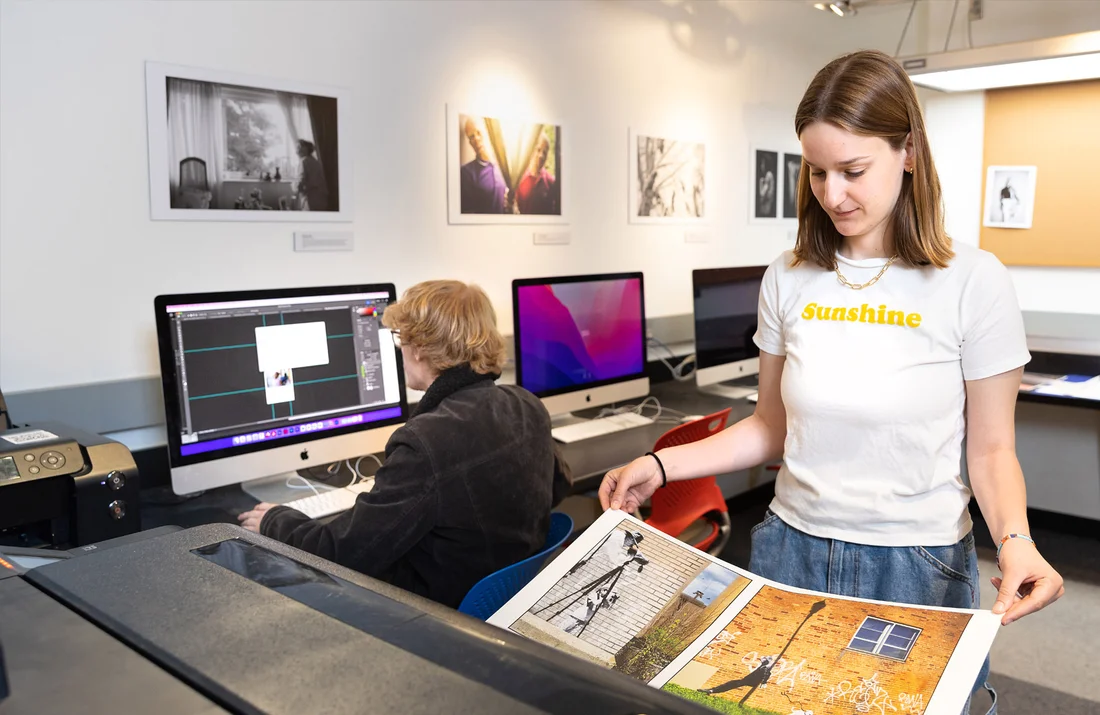 Student inspecting a print coming out of an Epson printer machine.