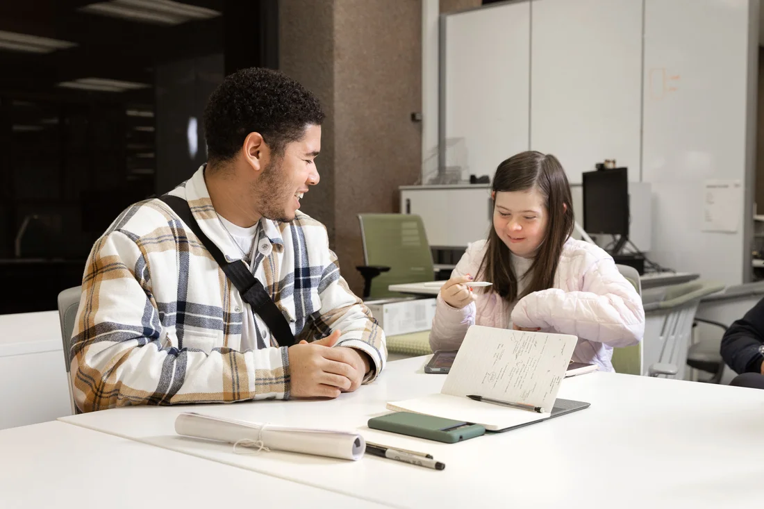 An InclusiveU student working with a classmate