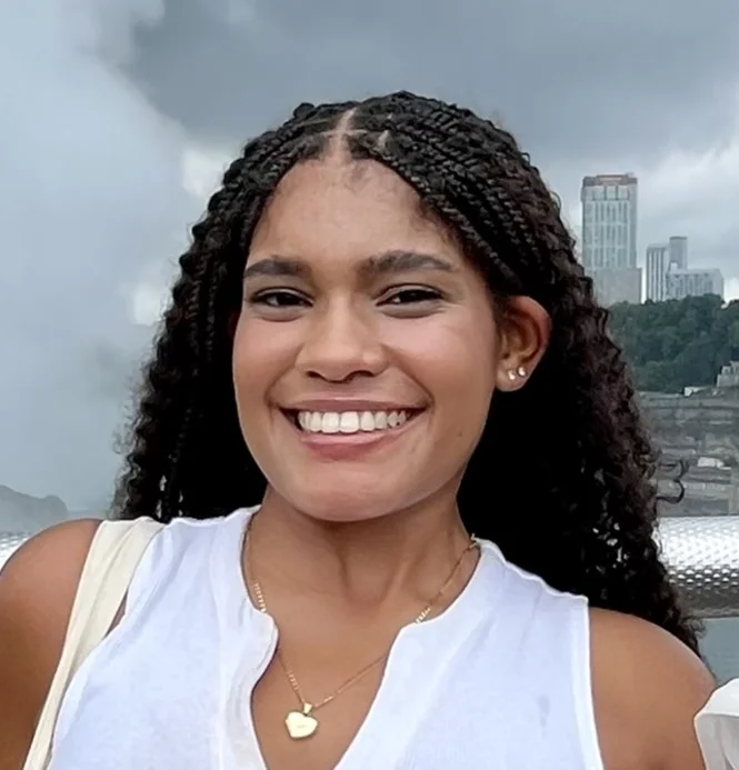A photo of Lisandra Pereyra smiling and standing outdoors in front of a city skyline