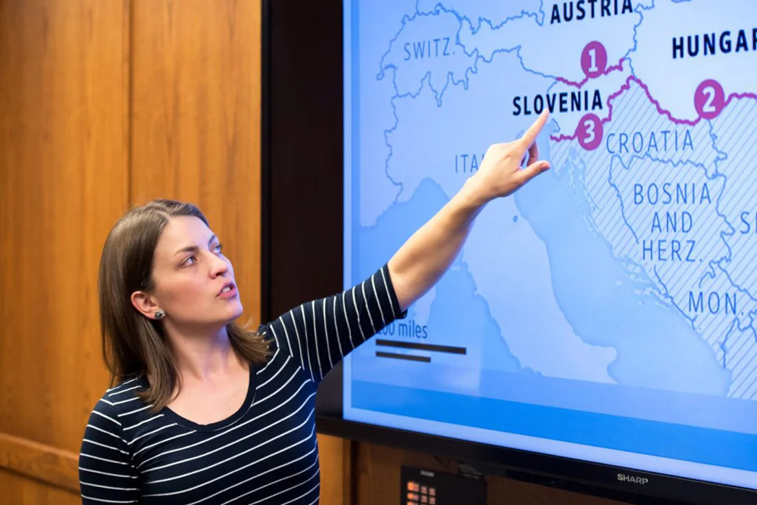 A student pointing at a map on a digital screen.