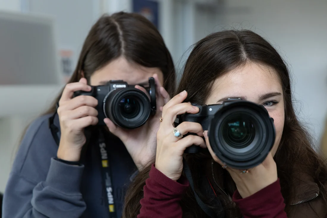 Two students in the multimedia, photography and design program using camera equipment.