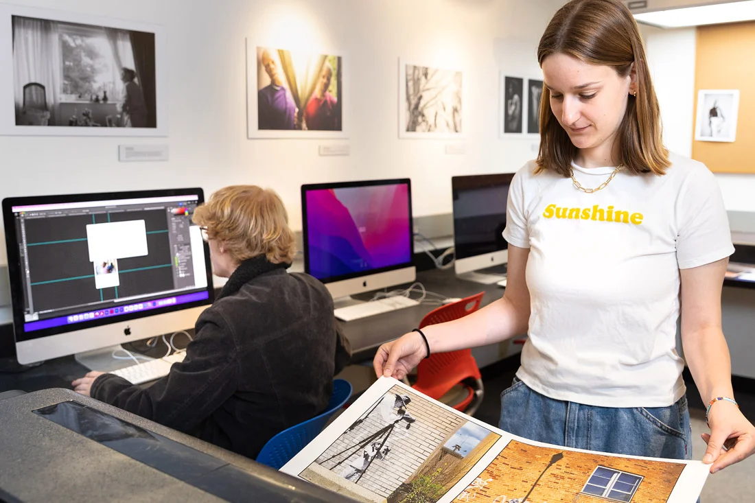 A student observes a printed page emerging from an Epson printer in a computer lab.