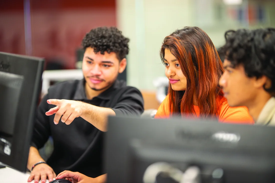 Bryan Reyes, Adya Parida, and Nahid Kalam sit in a computer lab