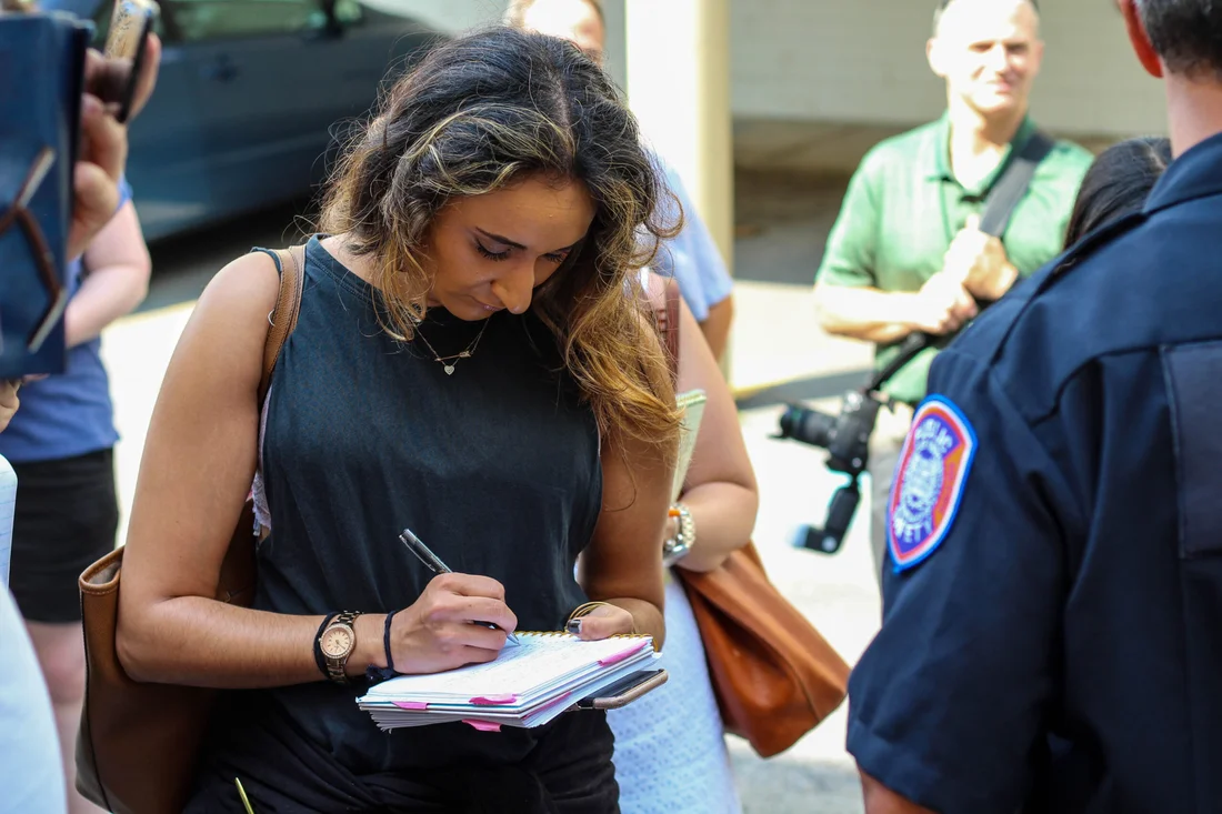 A student in the magazine, news and digital journalism program reporting on scene with a police officer.