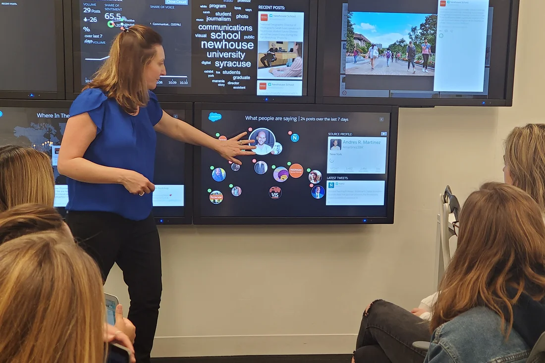 A professor in the public relations program standing in front of an interactive display.