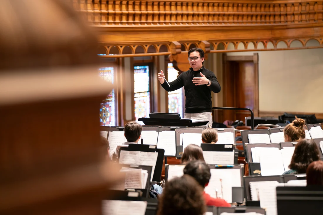 A person conducts an ensemble of musicians.