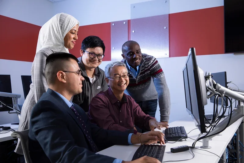 Students and professors collaborating at a computer.