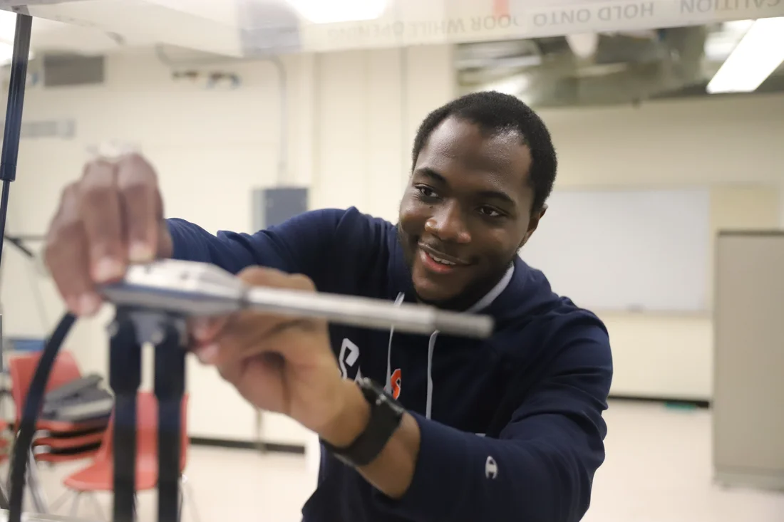 A student adjusts a piece of metal