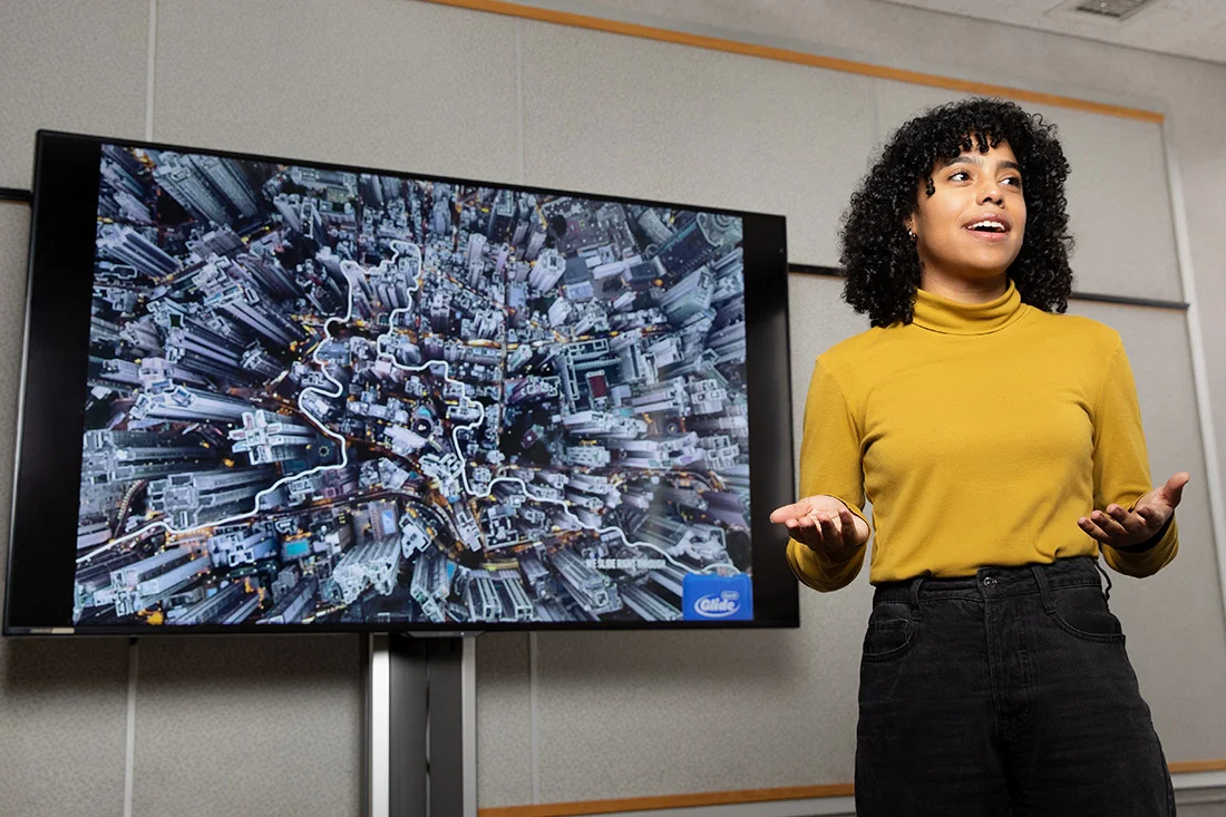 A student giving a presentation in front of a digital screen.