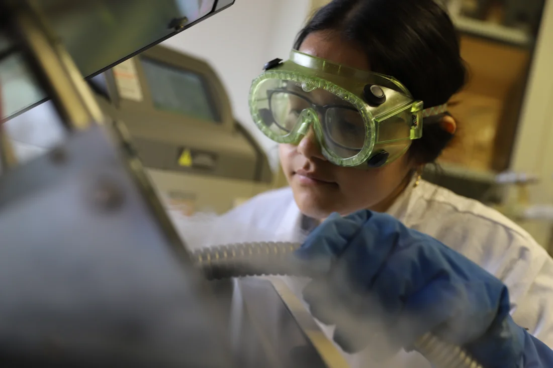 A student wearing safety goggles works in a lab